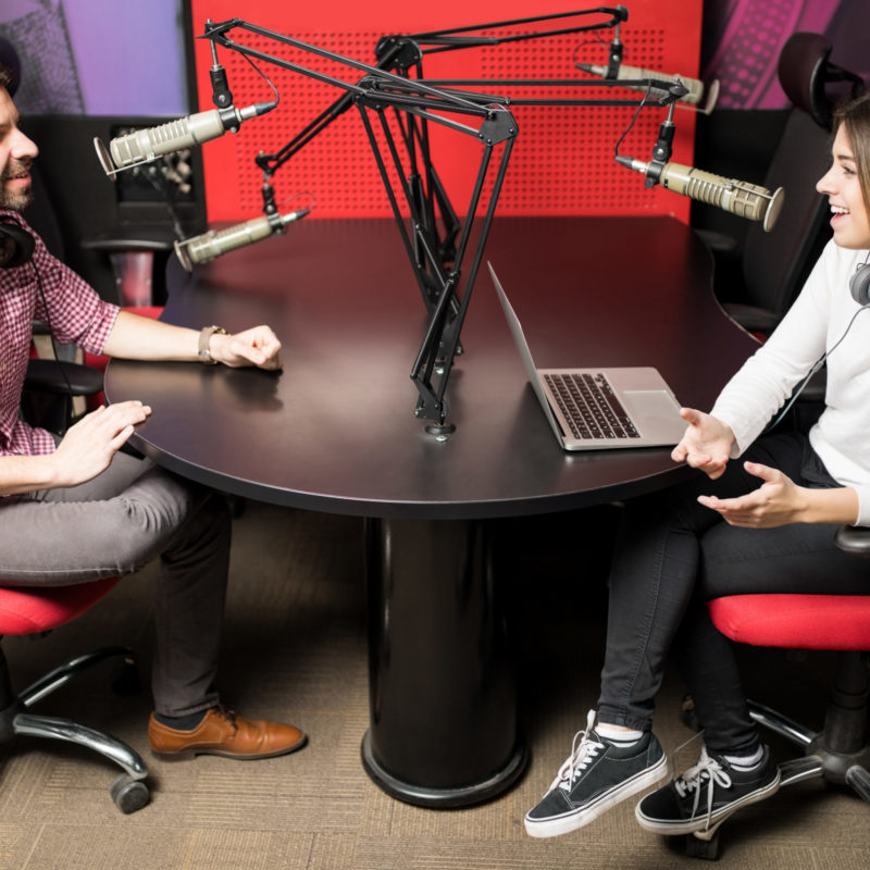 Couple of radio presenters talking with each other for radio show in a studio